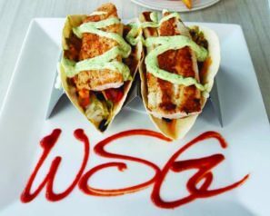 Two fish tacos on a square white plate that has WSG written on it in sauce