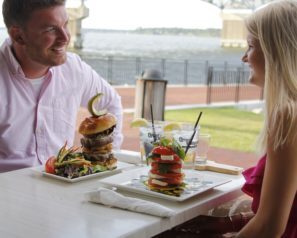 Man and woman eating a meal at a table along the river.