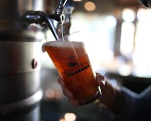 Bartender pouring a draft beer from a keg.
