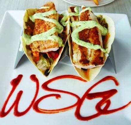 Two fish tacos on a square white plate that has WSG written on it in sauce