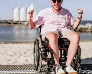 Man in a wheelchair on a mat on the beach