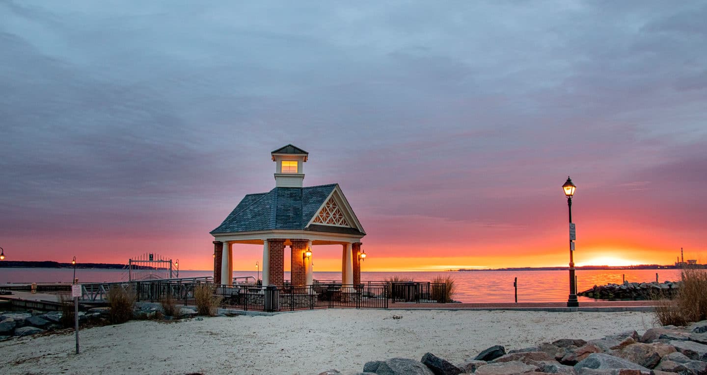 Yorktown beach hotel pergola on the river as the sun is setting with orange and dark blue hues.