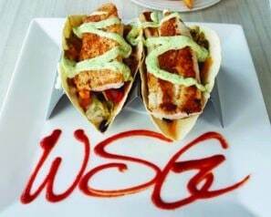 Two fish tacos on a square white plate that has WSG written on it in sauce