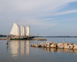 Old fashioned schooner with sails docked at a pier in the ocean